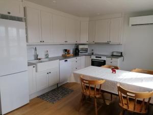 eine Küche mit weißen Schränken und einem Tisch mit Stühlen in der Unterkunft Dimgården in Leksand