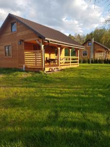 a log cabin with a large grass field in front of it at Gucio in Zwierzyniec