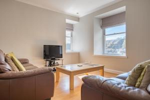 a living room with two couches and a tv at Stonehaven ground floor home with a spectacular harbour view. in Stonehaven