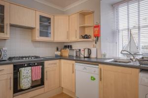 a kitchen with wooden cabinets and a white dishwasher at Stonehaven ground floor home with a spectacular harbour view. in Stonehaven