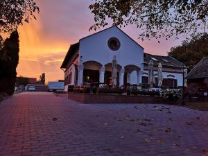 ein großes weißes Gebäude mit Sonnenuntergang im Hintergrund in der Unterkunft Diófa Panzió in Villány