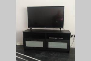 a flat screen tv sitting on top of a black entertainment center at The Cottage - Hot Tub - nr Glasgow - self check-in in Coatbridge