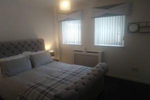 um quarto com uma cama grande e 2 janelas em The Cottage - Hot Tub - nr Glasgow - self check-in em Coatbridge