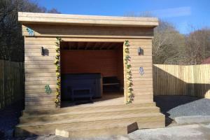 una casa di legno con una panca di The Cottage - Hot Tub - nr Glasgow - self check-in a Coatbridge