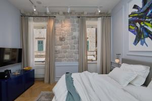 um quarto com uma cama grande e 2 janelas em Bota Palace em Dubrovnik