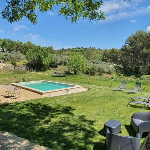 una piscina en un patio con sillas alrededor en Bastide Bellugue Maison d'hôtes réseau Bienvenue à La Ferme à 3 minutes de Lourmarin, en Cadenet