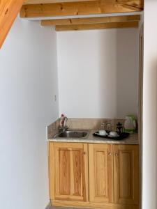 een keuken met houten kasten en een wastafel bij Glaros Guesthouse in Hydra