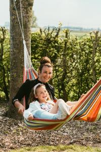 a woman and a little girl sitting in a hammock at de Flyboys in Watou