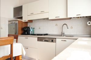 a kitchen with white cabinets and a sink at Appartamento L'arancio in Recanati