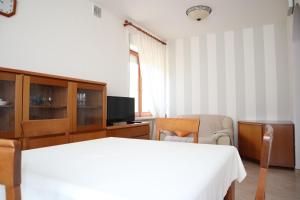a bedroom with a white bed and a television at Appartamento L'arancio in Recanati