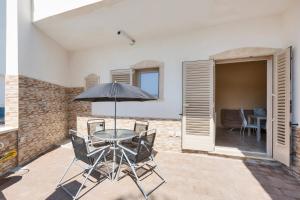 a patio with a table with chairs and an umbrella at Villino Vanessa by BarbarHouse in Torre Lapillo