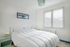 a white bedroom with a large bed and a window at Maison avec jardin à 140m de la Plage in Saint-Michel-Chef-Chef