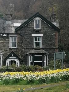 a painting of a house with flowers in front of it at Brooklands Guest House in Bowness-on-Windermere