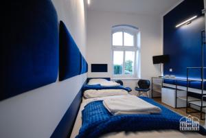 2 camas en una habitación con paredes azules y ventana en Franciszek przy Parku Szwedzkim, en Szczawno-Zdrój