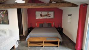レ・ゼペスにあるAu Petit Bignonのベッドルーム1室(赤い壁のベッド1台、テーブル付)