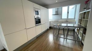a kitchen with white cabinets and a table and chairs at Pollensa Beach Loft in Port de Pollensa