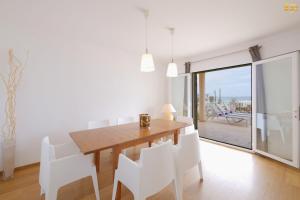 a dining room with a wooden table and white chairs at Can Picafort Auca in Can Picafort