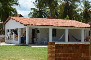 a white house with palm trees in the background at Baleia Beach - Casa de Praia in Itapipoca