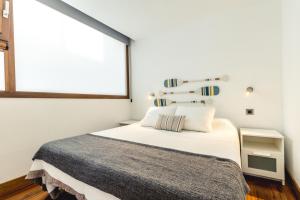 a bedroom with a white bed and a window at Melenara Beach Avenue Apt Shared Terrace in Melenara