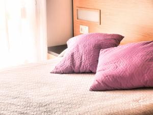 una camera con 2 cuscini viola su un letto di CORAZON DE LUANCO a Luanco