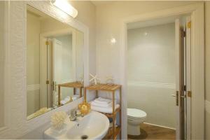ein Badezimmer mit Waschbecken, Toilette und Spiegel in der Unterkunft Casa Mediterraneo in Alcúdia + 20 Fotos