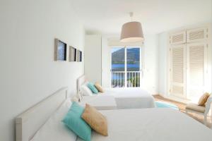 ein weißes Schlafzimmer mit 2 Betten und einem Fenster in der Unterkunft Casa Mediterraneo in Alcúdia
