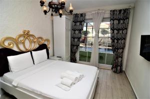 a bedroom with a white bed and a window at Grand Alaçatı Butik Hotel in Alaçatı