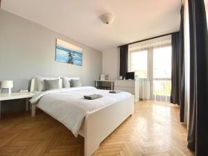 a bedroom with a white bed and a large window at Pokoje Gajowa in Lublin