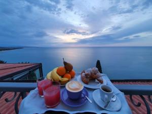 a table with a breakfast of fruit and coffee on a balcony at Luna Convento Copanello B&B in Stalettì