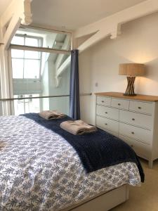 a bedroom with a bed and a dresser and a window at The Old English Rooms in Falmouth