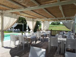 un restaurante con mesas y sillas blancas y una piscina en Agriturismo la Gioia en Scansano