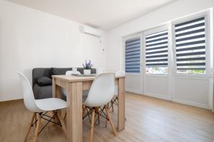 a dining room with a table and chairs and a couch at Apartmani Frane in Neum