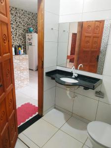 a bathroom with a sink and a mirror and a refrigerator at Doce Lar - Casa de Praia in Itapipoca