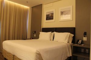 um quarto com uma cama grande com lençóis brancos e almofadas em Holiday Inn - Goiania, an IHG Hotel em Goiânia