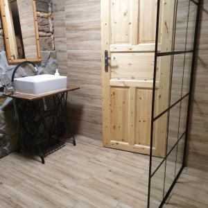 a bathroom with a sink and a wooden door at Chata góralska Wojtasówka in Kamesznica