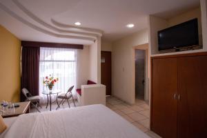 a hotel room with a bed and a living room at Hotel Arcos Aeropuerto in Veracruz