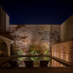 ein Gebäude mit einem Pool vor einer Backsteinmauer in der Unterkunft Tá Hotel de diseño in Querétaro