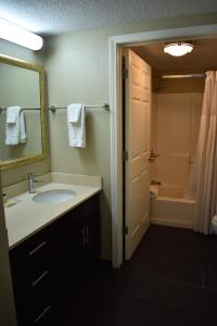 a bathroom with a sink and a mirror and a tub at Staybridge Suites Cranbury - South Brunswick, an IHG Hotel in Cranbury