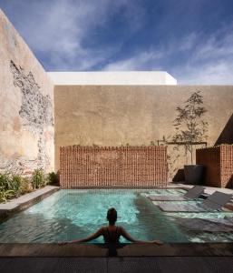una persona está sentada en una piscina en Tá Hotel de diseño en Querétaro