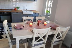 uma mesa de jantar branca com 4 cadeiras e velas em GUESTHOUSE MARIA / КЪЩА ЗА ГОСТИ МАРИЯ / GÄSTEHAUS MARIA em Karlovo