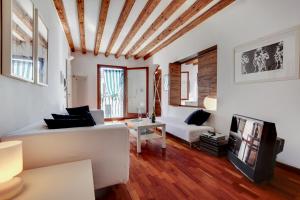 ein Wohnzimmer mit einem weißen Sofa und einem TV in der Unterkunft CA ANGELA VENETIAN APARTMENT M0270428215 in Venedig