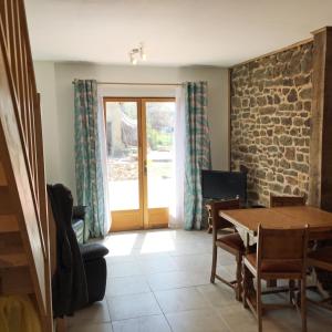 sala de estar con mesa y puerta de cristal en Les Maricotais Gîte L'Hirondelle, en Trévérien