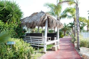 een bank met een rieten parasol en palmbomen bij Seven Maze Charming House in Bari