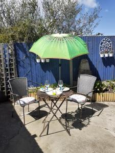 a table with a green umbrella and two chairs at Peaceful Garden Apartment in Herne Bay