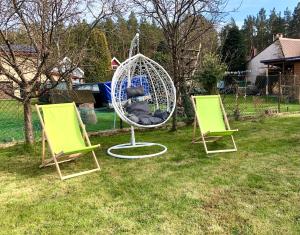 two green chairs and a swing in a yard at Przystań Rodzinna in Kopalino