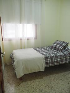 a bedroom with a bed with a plaid blanket and a window at Molinos II - Casitas Las Abuelas in Santa Cruz de la Palma