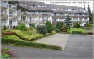 an apartment building with a parking lot in front of it at FeWo Eulennestchen-Harz in Altenau