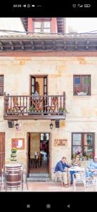 two people sitting at tables in front of a building at La Posada de Barro in Infiesto
