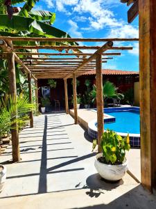 un patio con una pérgola de madera y una piscina en Casa com Wi-Fi e lazer em Porto de Pedras - AL, en Tatuamunha