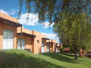 un edificio con un árbol delante de él en Hotel Posada Terrazas con pileta climatizada en Potrero de los Funes